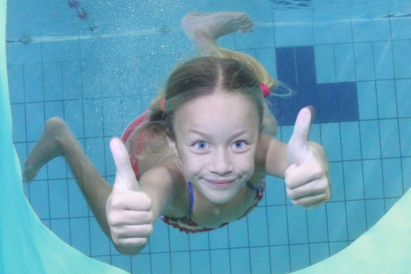 Meisje zwemt door gat in het zwembad heen
