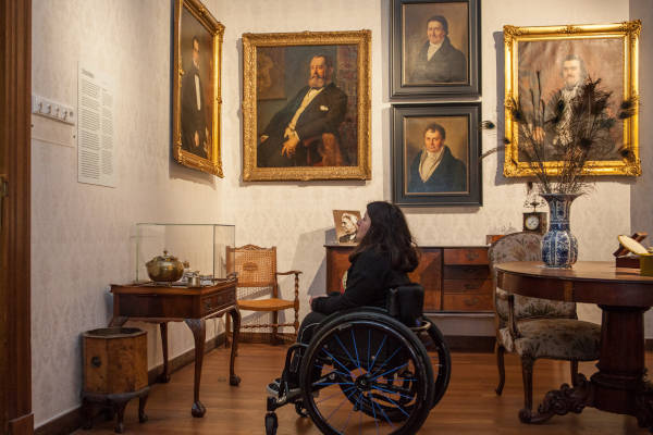 Vrouw kijkt naar de schilderijen aan de muur