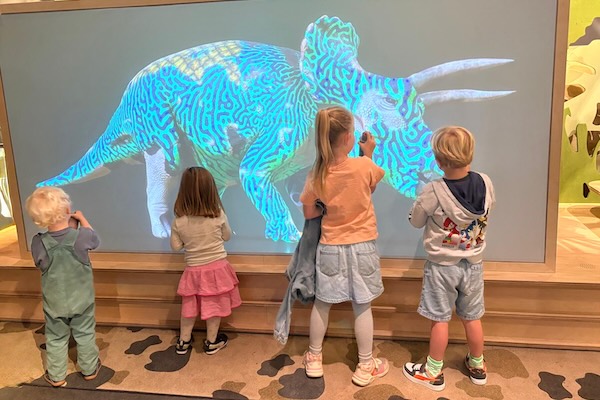 Kinderen kijken naar een digitale Triceratops