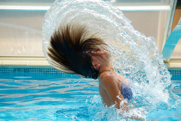 Meisje zwaait met haar haren in het zwembad