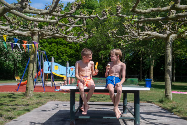 Kinderen eten ijsje op de pingpongtafel