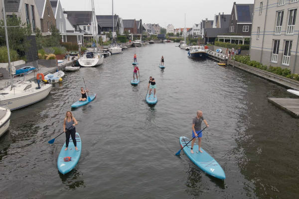 Groepje mensen aan het suppen langs huizen