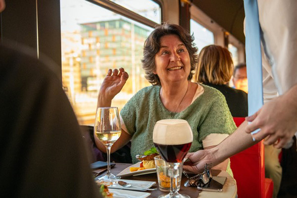 Mevrouw krijgt eten geserveerd tijdens het dineren in de trein