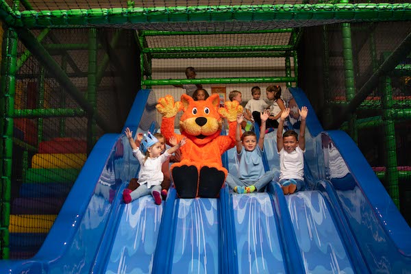 Kinderen glijden van de glijbaan samen met de mascotte van Ballorig