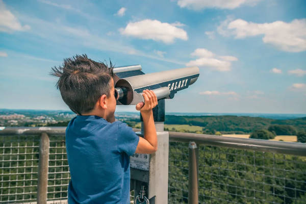 Jongen kijkt door de verrekijker naar het landschap