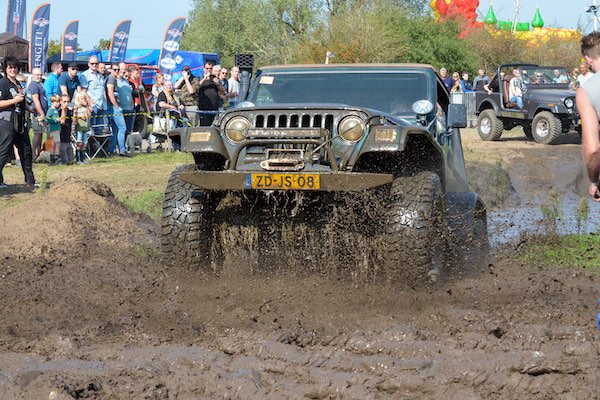 Auto rijdt door een grote modderpoel