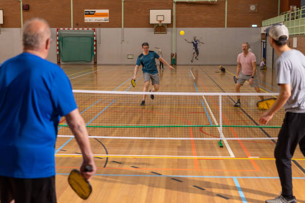 Mensen spelen pickleball binnen in een sporthal